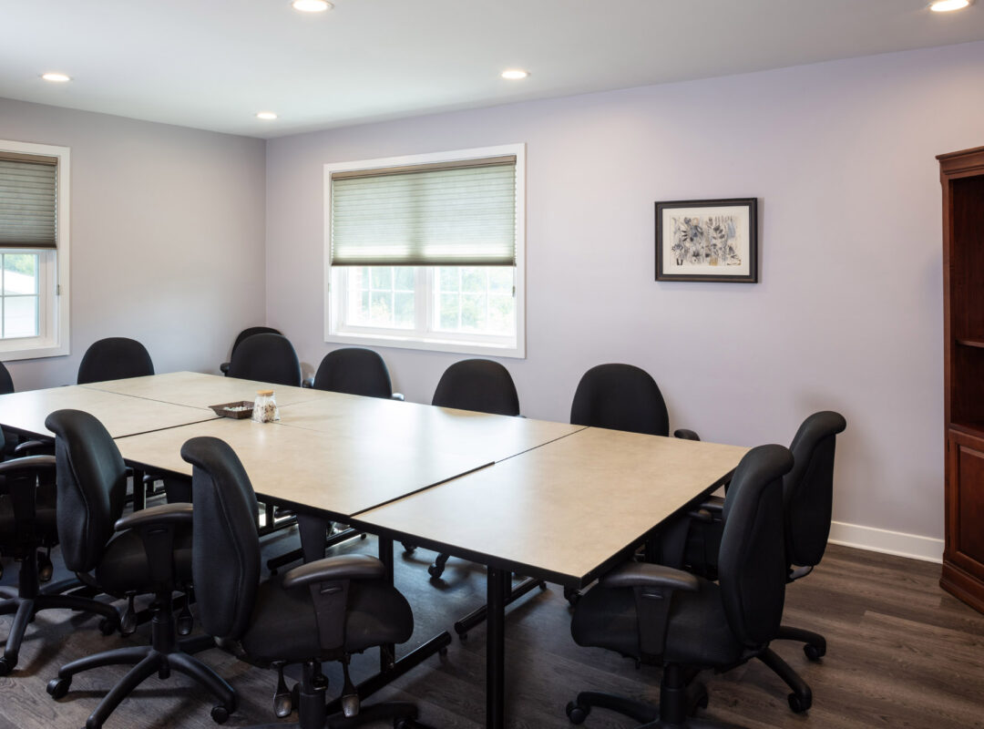 A long room with a long conference table and office chairs all around it.