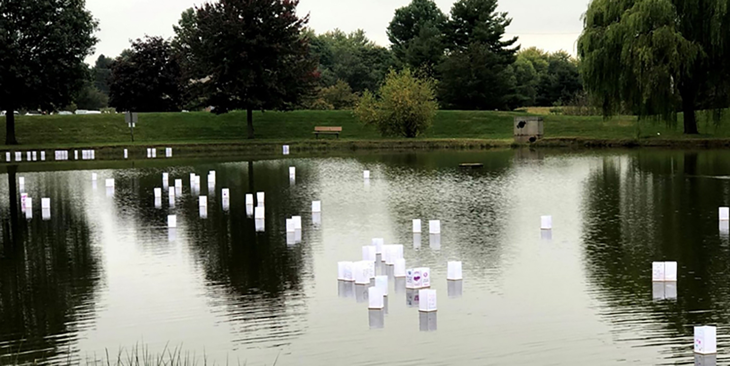 Paper lanterns floating across a lake in daylight.